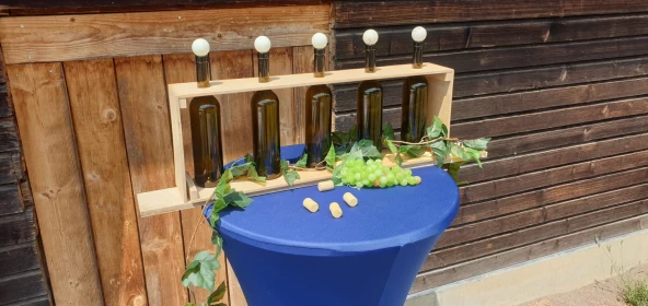 Weinflaschen in einem Holzkasten auf einem Stehtisch