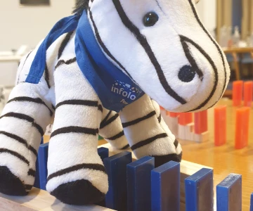 blaue Dominosteine führen unter einem Zebra-Kuscheltier durch