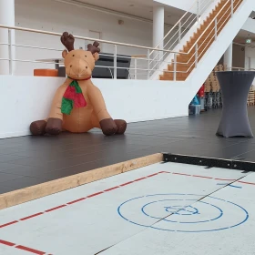Eisstockbahn in einer Halle mit einem aufblasbaren Rentier im Hintergrund