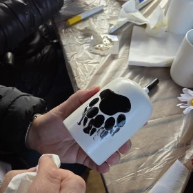 Person bemalt eine Keramik Tasse mit einer Wolfstatze