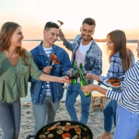 Menschen stoßen mit Bier am Lagerfeuer an