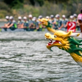 Spitze eines Drachenbootes in Form eines Drachens in Gelb und Grün
