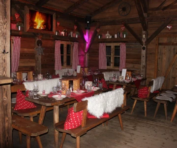 festlich geschmückte Tafel in einer Holzhütte