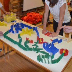 Menschen beim Bau einer Domino Kettenreaktion