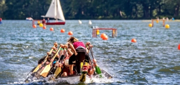 Drachenboot in der Frontansicht, in Hintergrund ein Segelboot