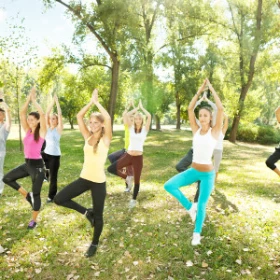 Personen einbeinig stehend und mit betenden Händen über dem Kopf