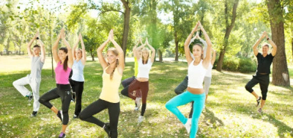 Personen einbeinig stehend und mit betenden Händen über dem Kopf