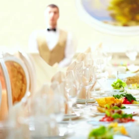 festlich dekorierte Tafel mit Teller, Gläsern und Speisen in der Mitte