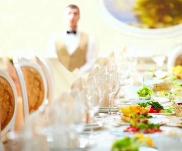 festlich dekorierte Tafel mit Teller, Gläsern und Speisen in der Mitte