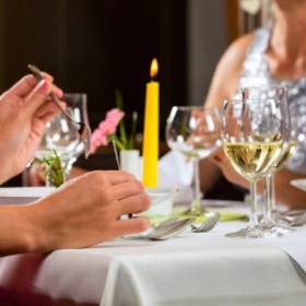 Personen essen an festlicher Tafel, Weingläser und gelbe Stabkerze steht auf dem Tisch