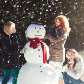 Drei Frauen bauen einen Schneemann