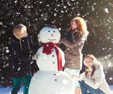 Drei Frauen bauen einen Schneemann
