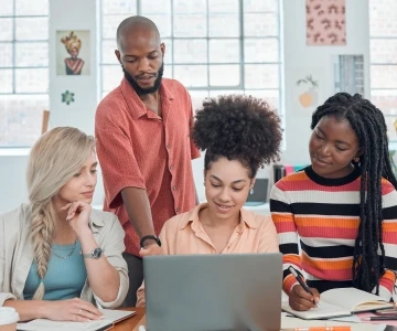 Gruppe schaut gespannt auf einen Laptop