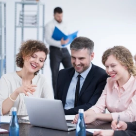 Gruppe bespricht sich und macht Notitzen an einem Laptop