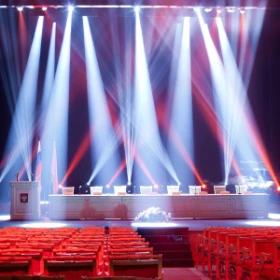 Rednerpult mit 8 Sitzplätzen auf einer Bühne wird angeleuchtet