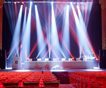 Rednerpult mit 8 Sitzplätzen auf einer Bühne wird angeleuchtet