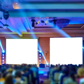 Zwei Leinwände stehen vor einem Publikum