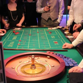 Eine Gruppe von Menschen steht um einen Casinotisch