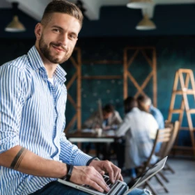 Mann hat seinen Laptop auf den Beinen und er sitzt in einem Büro