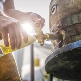 ein Bierfass wird angezapft. Bier läuft auf dem Fass in ein Bierglas