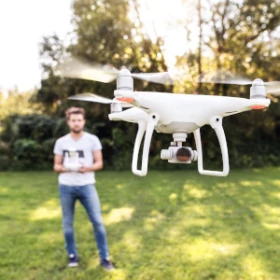 Nahaufnahme einer Drohne, Person die stuert im Hintergrund