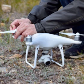 Person baut an einer Drohne die auf dem Boden steht