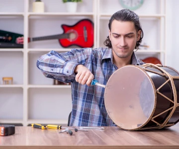 Mann baut eine Trommel und spannt Trommelfell