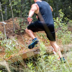 Mann springt über einen Baumstamm im Wald