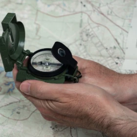 Person hält einen Kompass über eine Karte