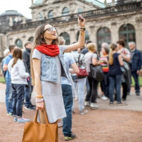 Frau mit Handy in der Hand macht ein Foto von einer Sehenswürdigkeit