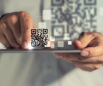 zwei Hände halten ein Tablet, ein QR-Code schwebt über dem Tablet