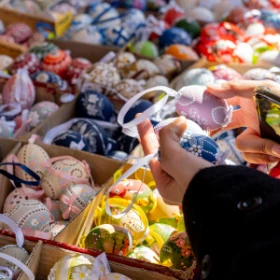 Person hält zwei bemalte Ostereier an einem Marktstand in der Hand