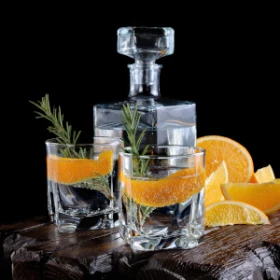 2 Gin Gläser vor einer Karaffe mit Orangen
