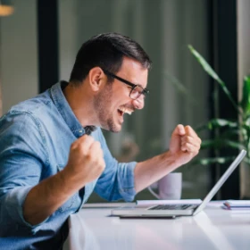 Man sitzt vor seinem Laptop und freut sich