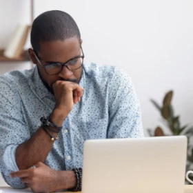 Man schaut nachdenklich auf seinen Laptop