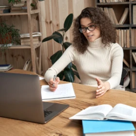Frau coacht vor ihrem Laptop die virtuellen Teilnehmer