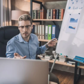 Mann erklärt anhand einer Grafik auf dem Flipchart etwas