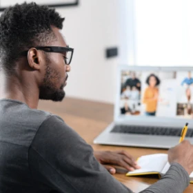 Mann macht sich Notizen von einem virtuellen Seminar
