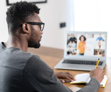 Mann macht sich Notizen von einem virtuellen Seminar