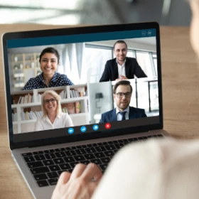 Auf dem Laptopn sieht man ein Meeting mit 4 Personen