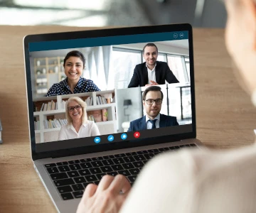 Auf dem Laptopn sieht man ein Meeting mit 4 Personen