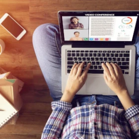 Person sitzt auf dem Boden mit ihrem Laptop auf den Beinen