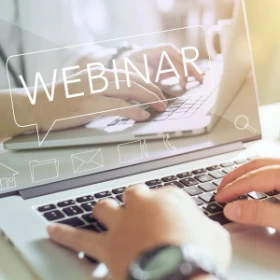 ein Laptop auf dem ein Bild zusehen ist, auf dem "Webinar" steht