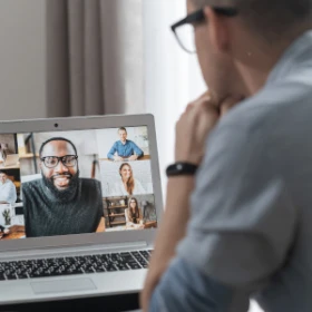 Mann sitzt gespannt vor seinem Laptop und hört dem Meeting zu
