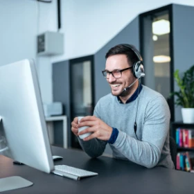 Mann sitzt vor seinem Rechner und freut sich