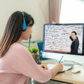 Frau hört gespannt einem Seminar zu und macht sich Notizen