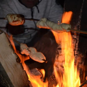 Personen halten Stockbrot über ein Lagerfeuer