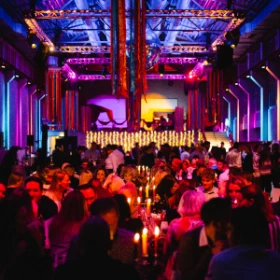 Festhalle mit orientalischer Dekoration in hellblau, lila und orange, lange Tafeln, Kerzenständer auf den Tischen