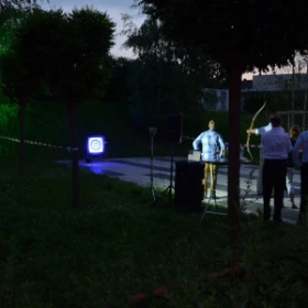 Personen beim Bogenschießen bei Nacht auf eine beleuchtete Zielscheibe
