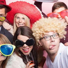 Personen machen mit Perücken und Brillen ein gemeinsames Bild